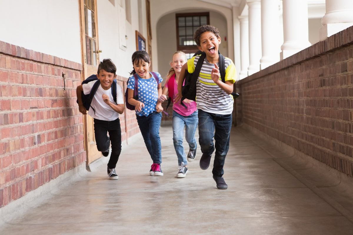 Children running down a school hallway with brick walls.