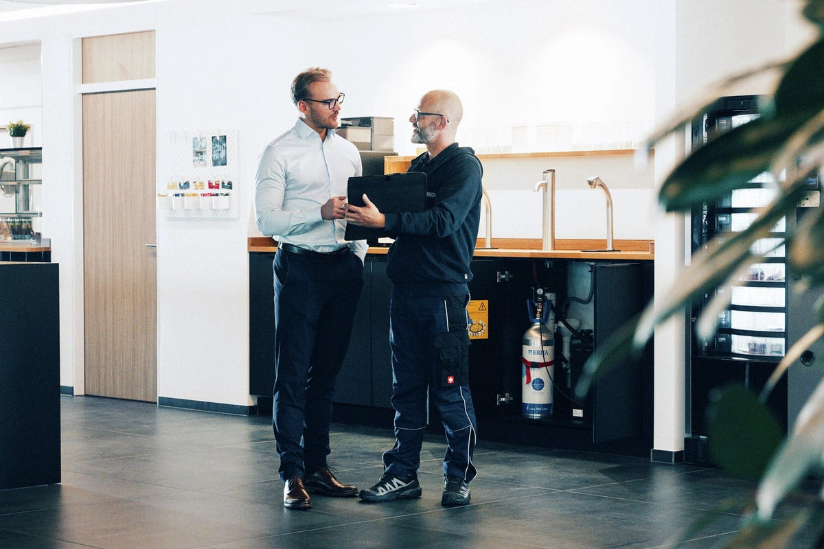 Two men standing in a modern office kitchen area.