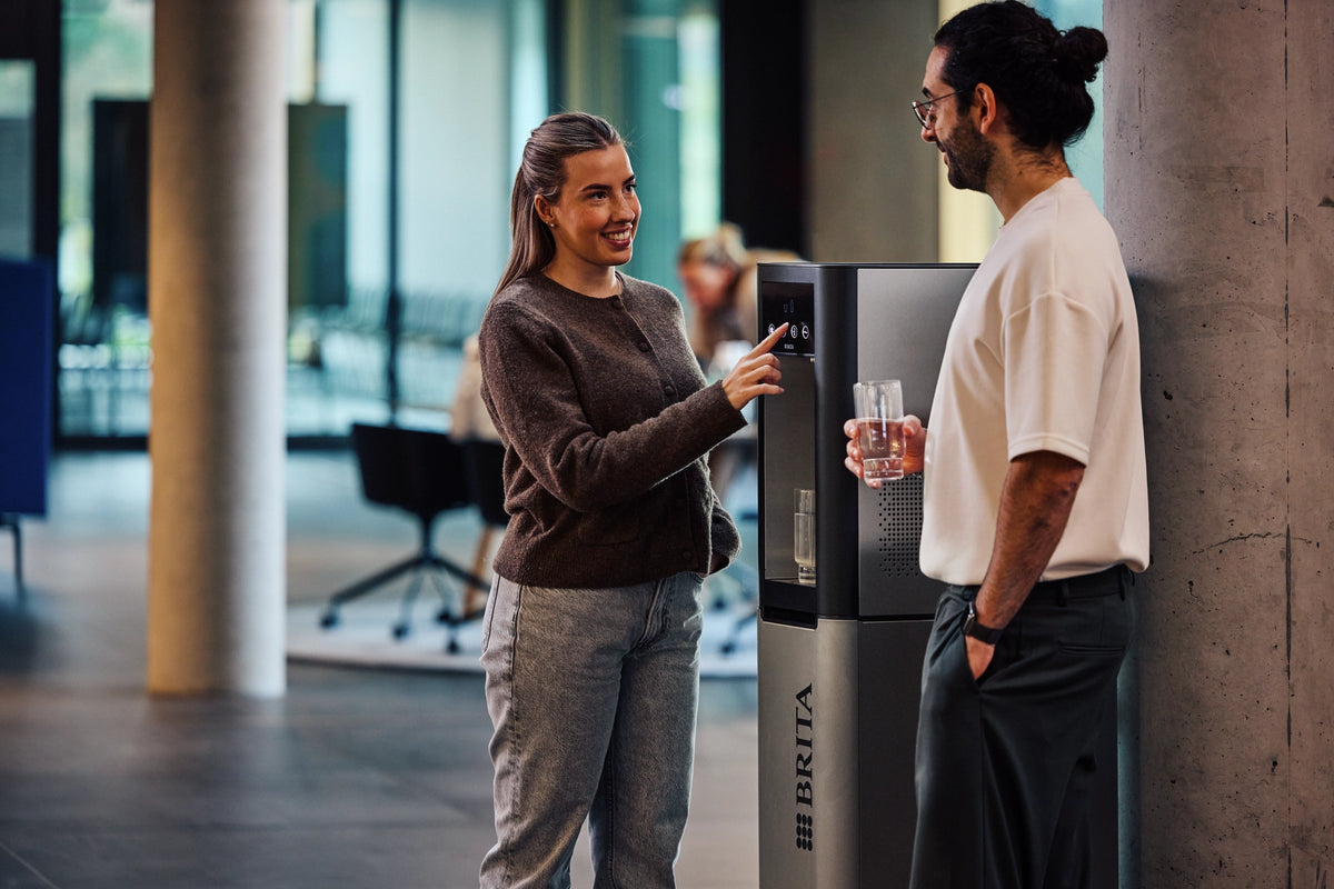 Two people interacting with a BRITA Top Pro in an modern office setting.