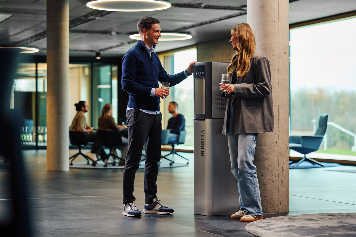 Two people at a water dispenser Top Pro in an office setting