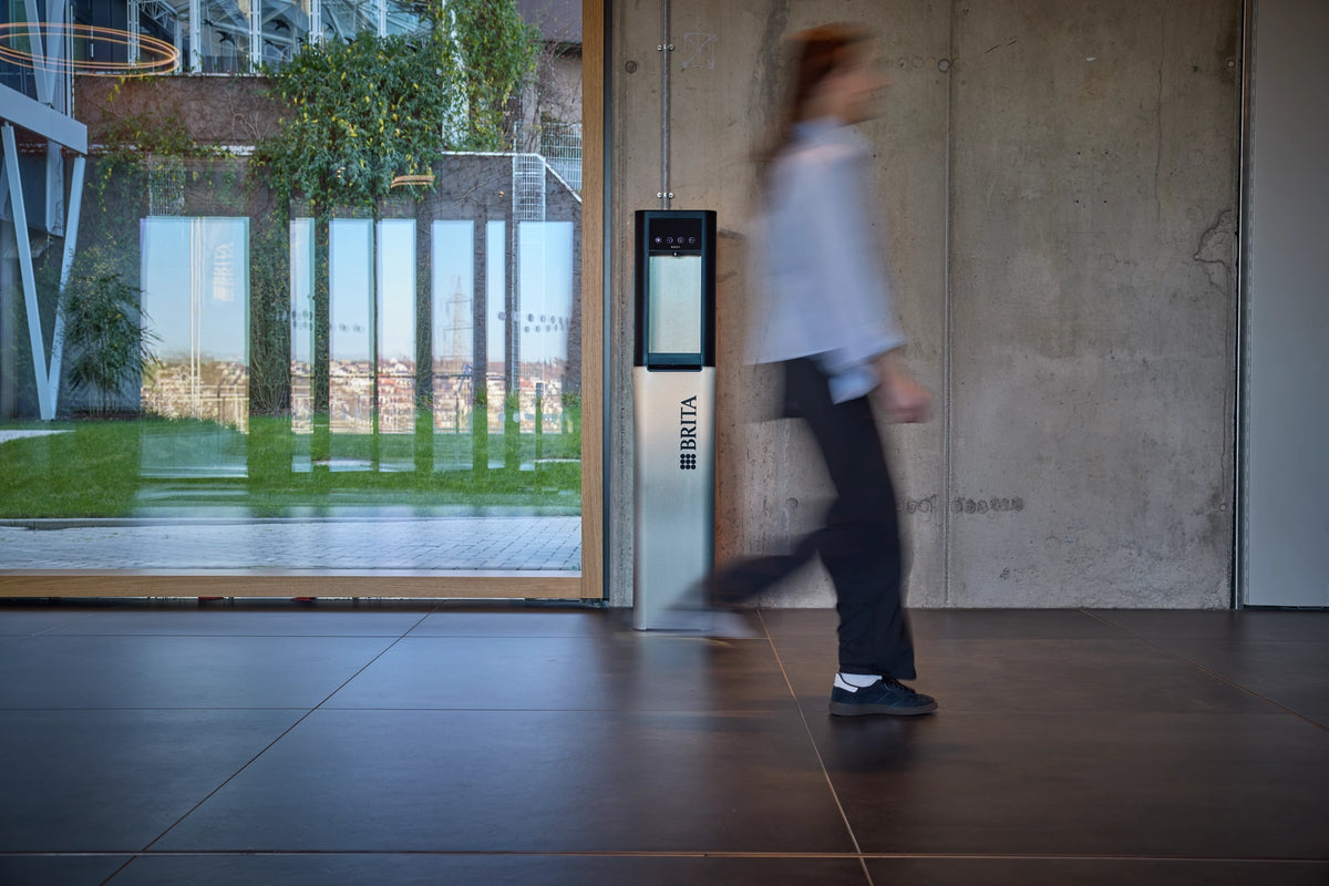 Person walking past a modern building entrance with a BRITA Top Pro.